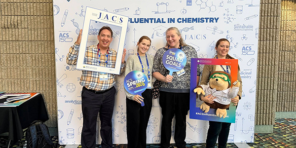 Four people posing in front of an American Chemical Society (ACS) backdrop at the Spring 2026 conference.